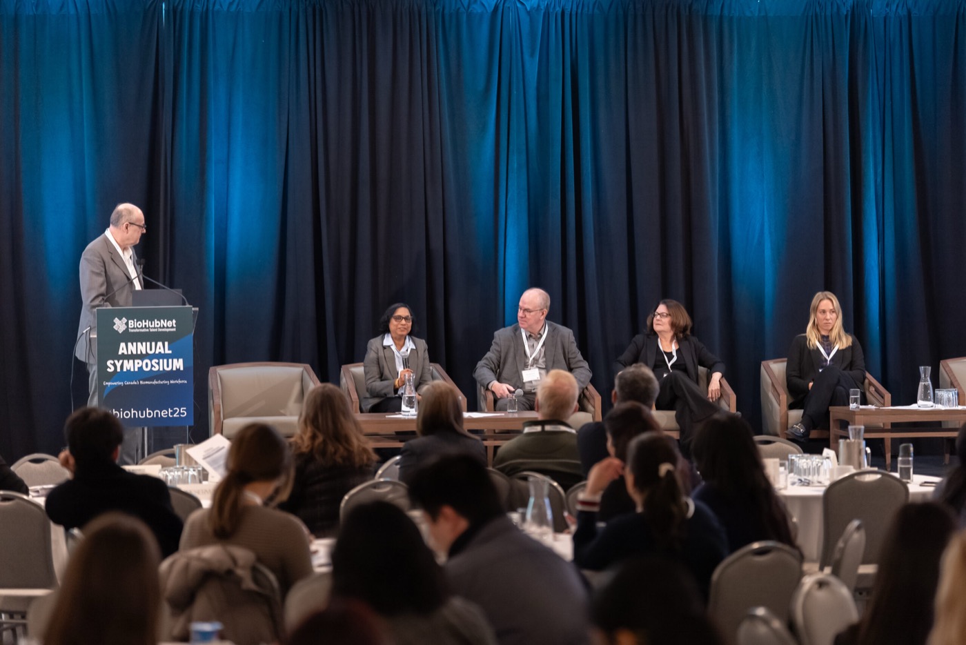 Panelists seated on stage during the 2025 symposium